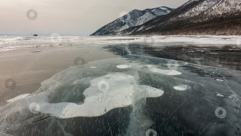 Скачать На гладком, блестящем льду замерзшего озера видны трещины и пузырьки замерзшего метана фотосток Ozero