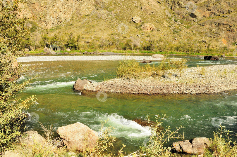 Скачать Извилистое русло бурной горной реки с прозрачной бирюзовой водой течет по узкому каньону солнечным летним днем. фотосток Ozero