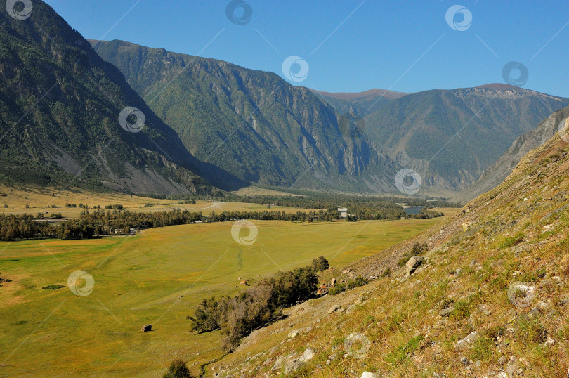 Скачать Большая живописная долина, окруженная горами, залитая солнечным светом. фотосток Ozero