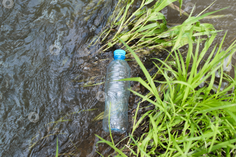 Скачать Загрязнение природы, концепция экоклогии. Пластиковая бутылка, плавающая в воде, вид сверху. Выбрасывайте пластиковые отходы в ручей, озеро или реку на открытом воздухе. фотосток Ozero