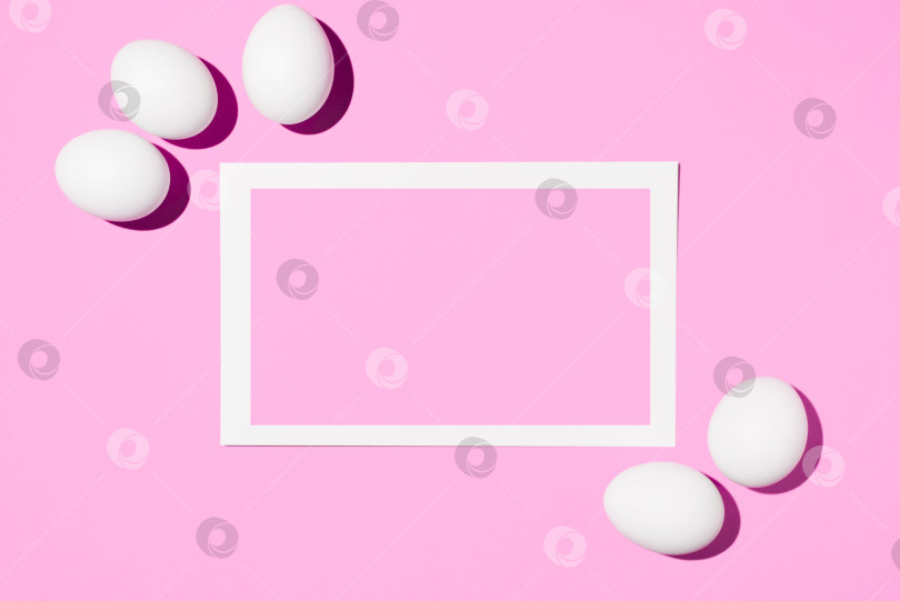 Скачать Пасхальный макет. Рамка с местом для текста и белыми яйцами на розовом фоне. Ровная поверхность, свободное место для копирования. Поздравительная пасхальная открытка. фотосток Ozero