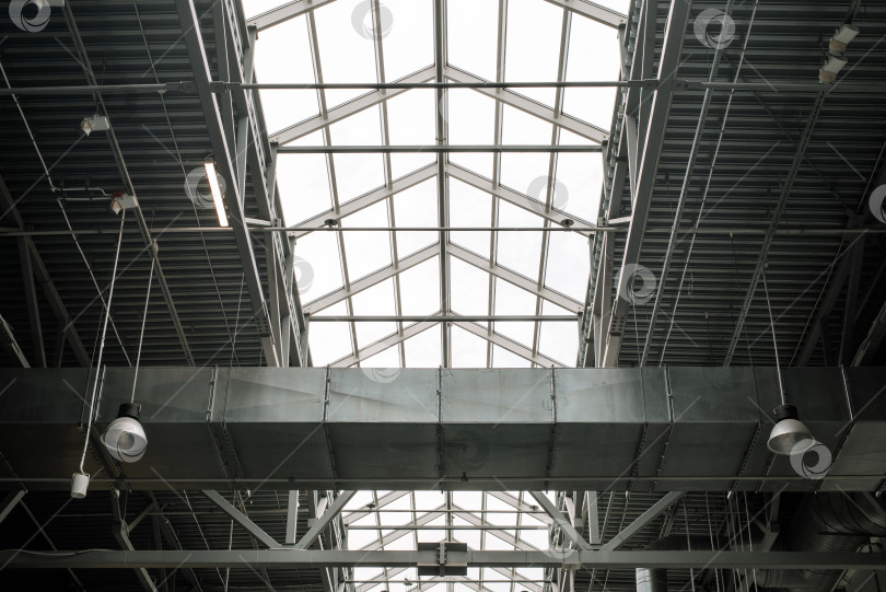Скачать Металлическая конструкция крыши торгового центра, внутри помещения. Встроенные окна в верхней части для освещения. Архитектура крупного промышленного здания фотосток Ozero