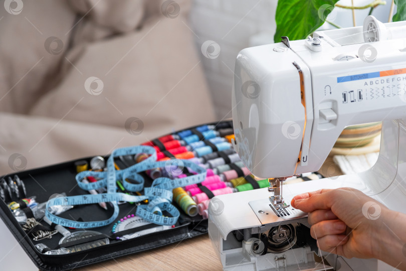 Скачать Женская рука крупным планом шьет тюль на электрической швейной машинке. Филли фотосток Ozero