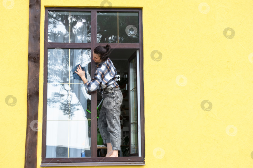 Скачать Женщина вручную моет окно дома тряпкой с  фотосток Ozero