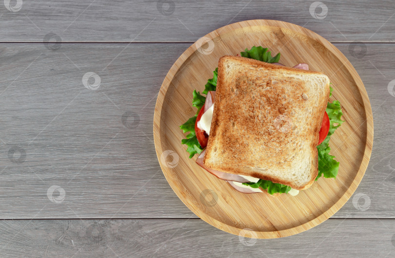Скачать Вкусный сэндвич с ветчиной, свежим салатом и помидорами подается на тарелке. Вид сверху. фотосток Ozero