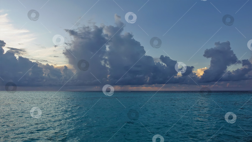 Скачать Небо и океан. Над спокойной бирюзовой гладью воды плывут голубые и золотистые облака фотосток Ozero