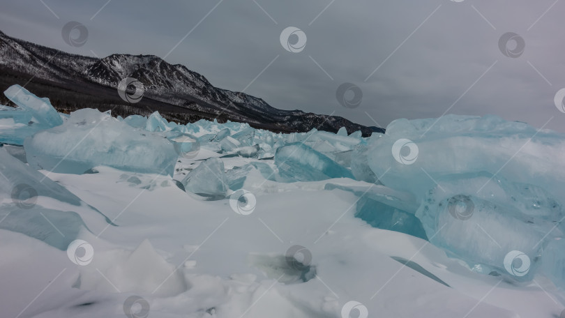 Скачать Глыба бирюзовых ледяных торосов в беспорядке лежит на снегу. фотосток Ozero