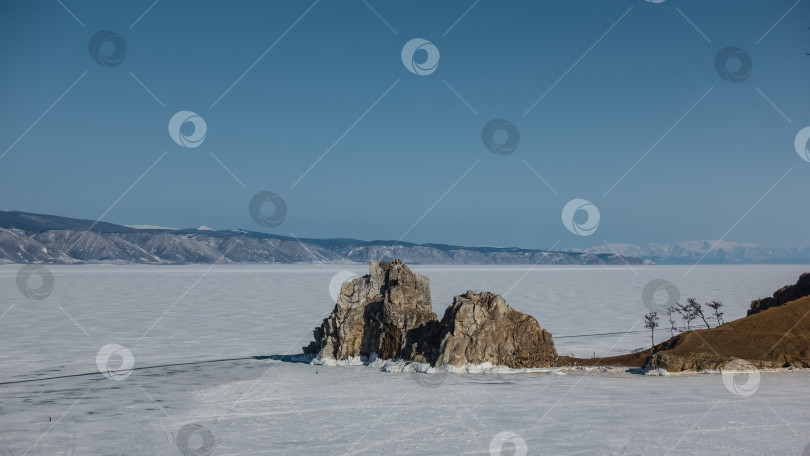 Скачать Живописная двуглавая скала, лишенная растительности, возвышается на замерзшем озере Байкал. фотосток Ozero