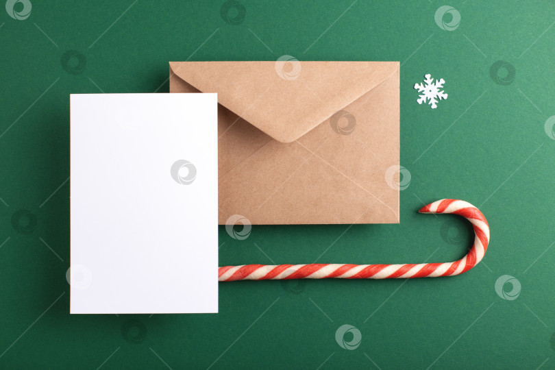Скачать Белый лист бумаги, почтовый конверт и зимний декор на зеленом фоне. фотосток Ozero