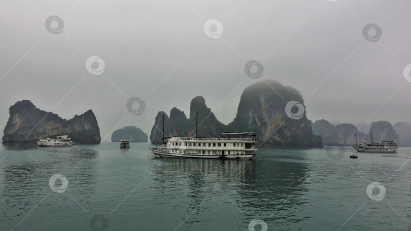 Скачать Туристические суда проплывают по спокойным водам залива Халонг. фотосток Ozero