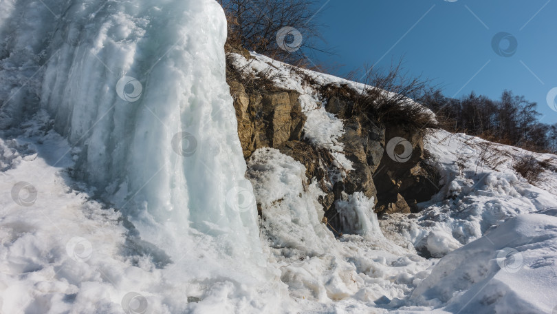 Скачать Тающий снег и сосульки на склоне холма. Сухая трава на камнях. фотосток Ozero