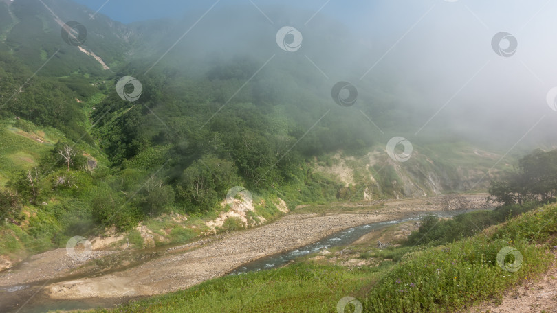 Скачать Река течет по каменистому руслу в долине гейзеров. Вода пенится. фотосток Ozero