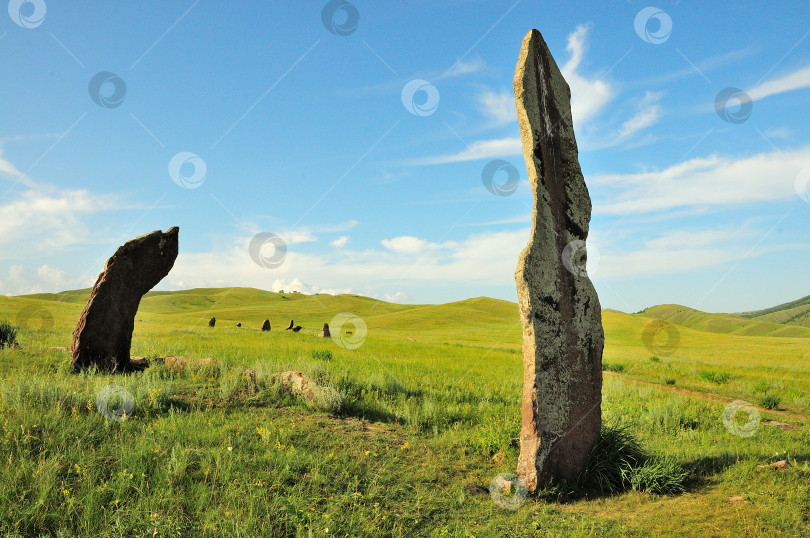 Скачать Высокие каменные менгиры на месте древнего захоронения в живописной долине, окруженной холмами. фотосток Ozero