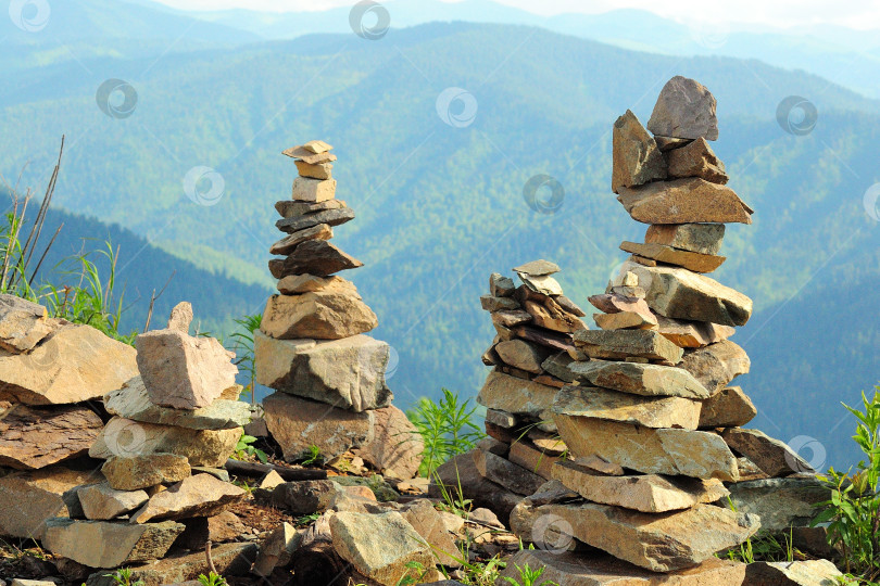 Скачать Ритуальные каменные пирамиды на вершине высокой горы с видом на холмы, поросшие густым хвойным лесом. фотосток Ozero
