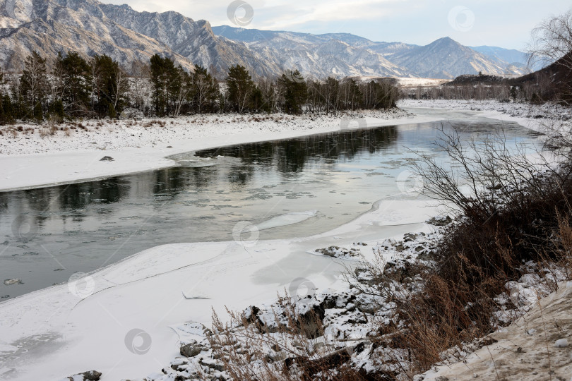 Скачать Поляна на ледяном русле красивой реки, протекающей по заснеженной долине, окруженной высокими горами. фотосток Ozero