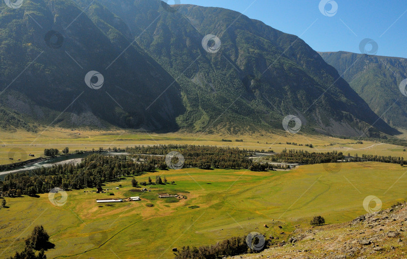 Скачать Живописная летняя долина и бурная река, текущая в окружении высоких гор. фотосток Ozero