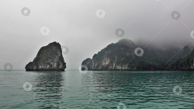 Скачать Причудливые острова скрыты в туманной дымке. Крутые склоны и зеленая растительность. фотосток Ozero