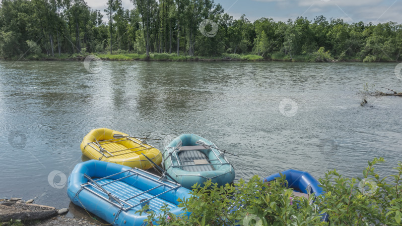 Скачать На реке недалеко от берега стоят разноцветные надувные лодки. фотосток Ozero