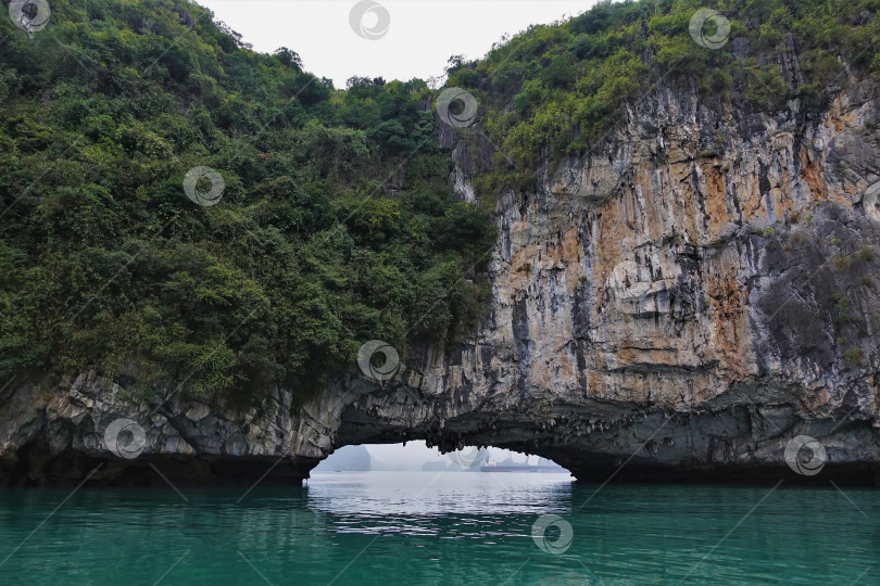 Скачать Причудливый скалистый остров образует арку над водой залива Халонг. фотосток Ozero