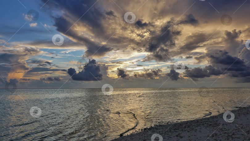 Скачать Золотой закат на Мальдивах. Солнце высвечивает облака на голубом небе. фотосток Ozero