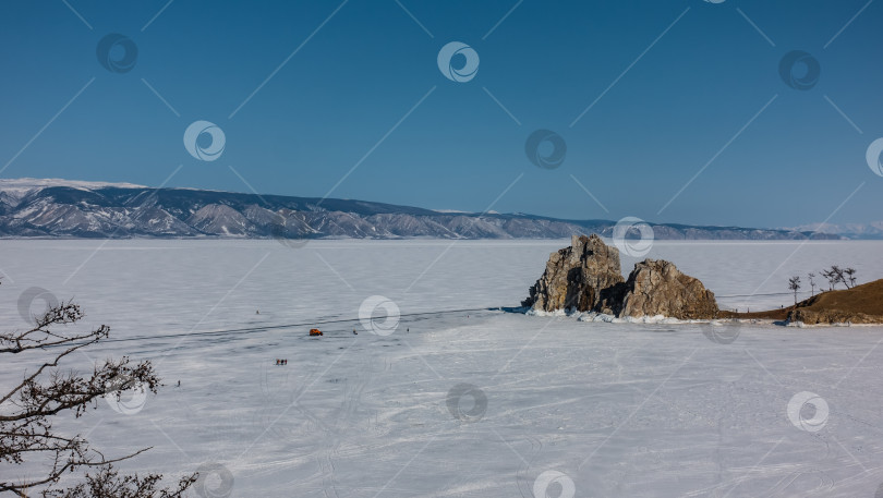 Скачать Двуглавая гранитная скала, лишенная растительности, возвышается над замерзшим озером. фотосток Ozero