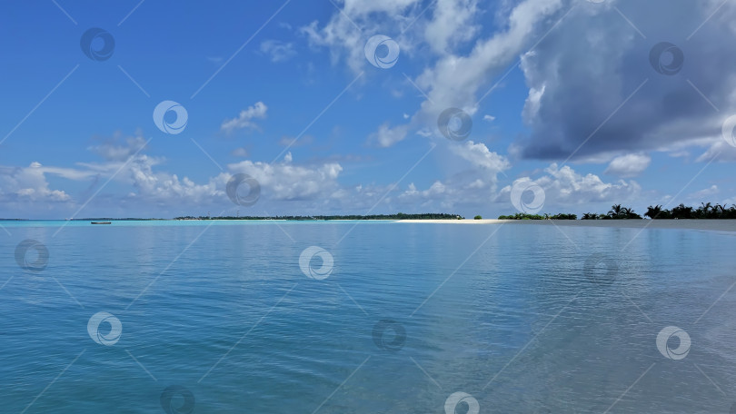 Скачать Аквамариновый океан спокоен. Вдалеке виднеется остров с песчаным пляжем, пальмами. фотосток Ozero