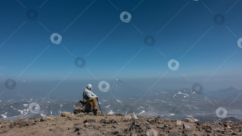 Скачать Мужчина сидит на камнях на краю обрыва. Голова опущена. фотосток Ozero