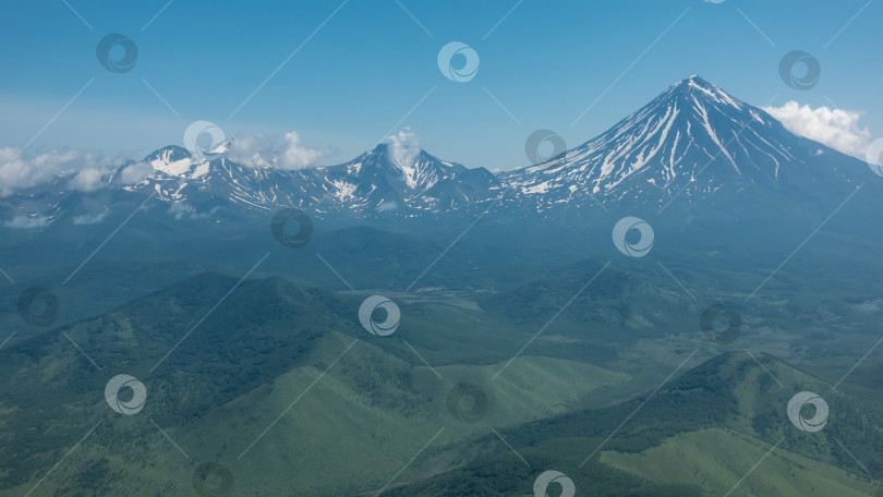 Скачать Красивые конические вулканы с заснеженными склонами на фоне голубого неба. фотосток Ozero
