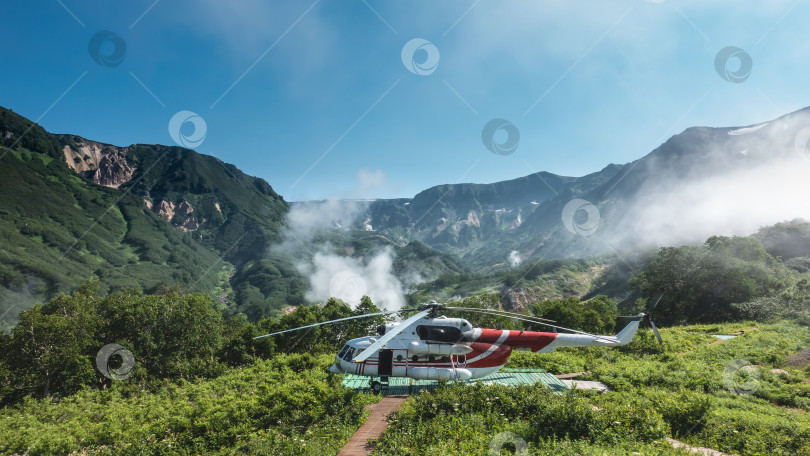 Скачать На зеленом лугу, на посадочной площадке, стоит вертолет. фотосток Ozero