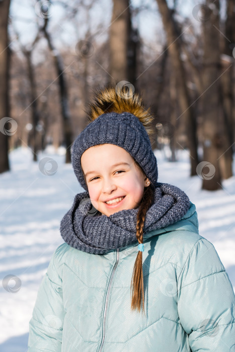 Скачать Улыбающаяся девушка в теплой одежде в зимнем парке в морозный солнечный день фотосток Ozero