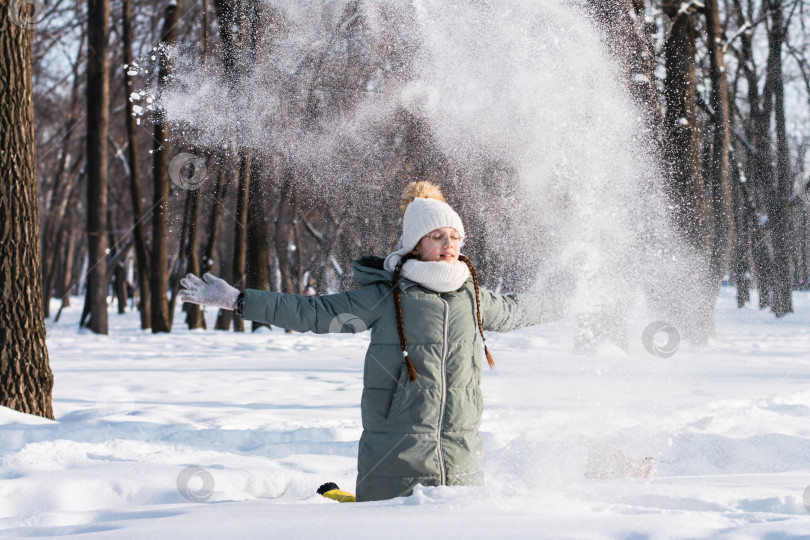 Скачать Девочка в очках и в теплой одежде играет со снегом зимой фотосток Ozero