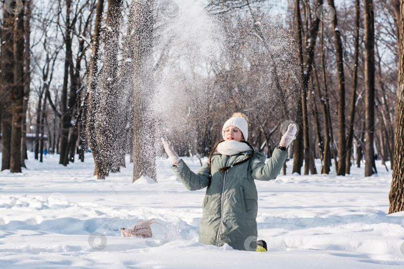 Скачать Девушка в очках и теплой одежде разбрасывает снег зимой для фотосток Ozero