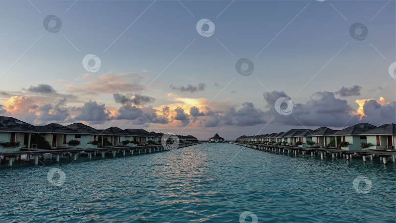 Скачать Два ряда вилл на воде тянутся над аквамариновым океаном.  Мальдивы. фотосток Ozero