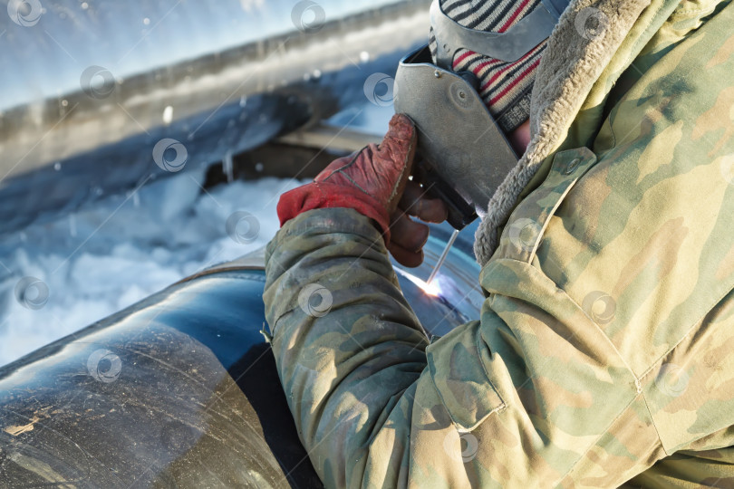 Скачать сварщик выполняет сварку трубопровода в зимних условиях фотосток Ozero