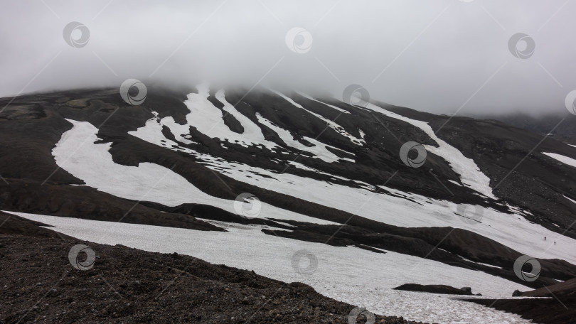 Скачать На склоне горы, лишенном растительности, видны причудливые пятна растаявшего снега. фотосток Ozero