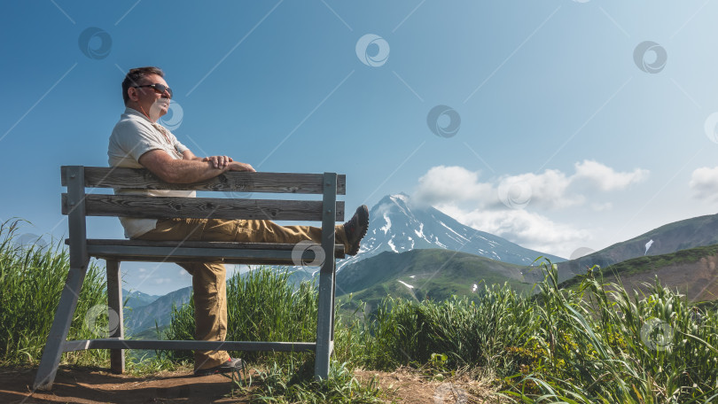 Скачать Мужчина в темных очках сидит на скамейке и улыбается. фотосток Ozero