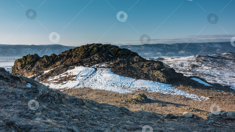 Скачать Живописная гранитная скала на фоне голубого неба и горного хребта. фотосток Ozero