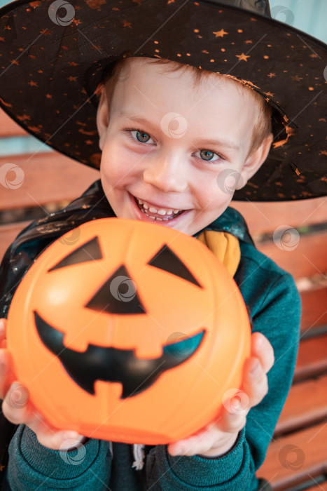 Скачать Дети на Хэллоуин. Милый маленький мальчик, ребенок в шляпе ведьмы с оранжевым ведерком для конфет Jack O Lantern. счастливого Хэллоуина. фотосток Ozero