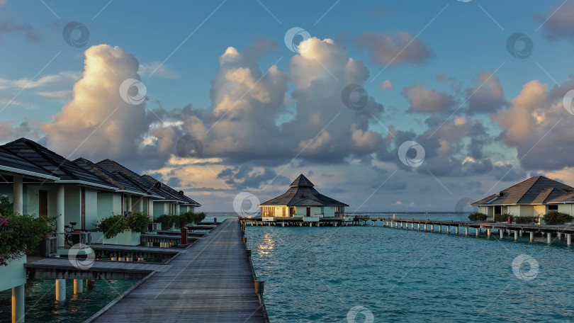 Скачать Утро на Мальдивах. Два ряда вилл на воде тянутся над аквамариновым океаном. фотосток Ozero