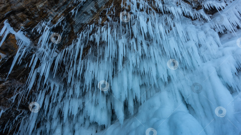 Скачать Ряды тонких длинных сталактитовых сосулек свисают с потолка пещеры. фотосток Ozero