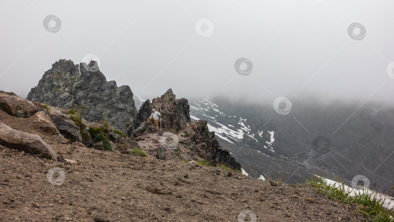 Скачать Мужчина с треккинговой палкой стоит на вершине горы. фотосток Ozero