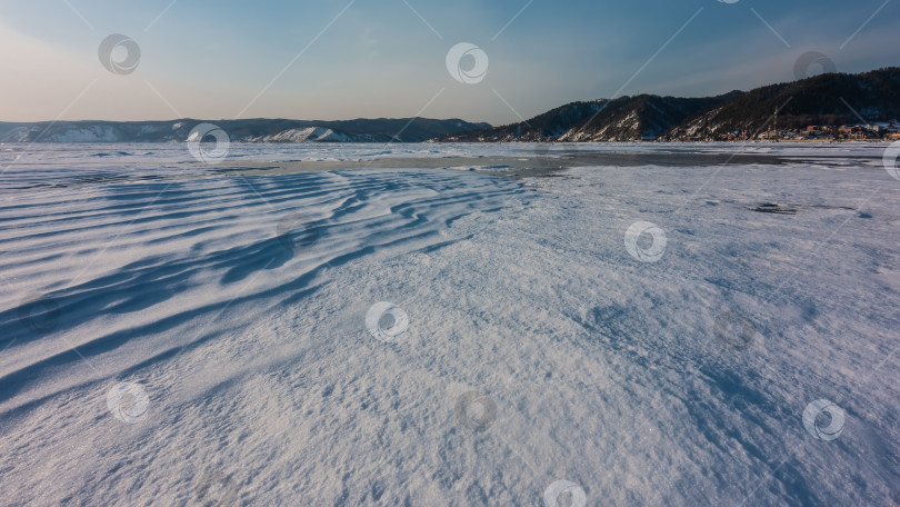 Скачать Замерзшее озеро Байкал. Снег на поверхности образует волнистые узоры, похожие на дюны. фотосток Ozero