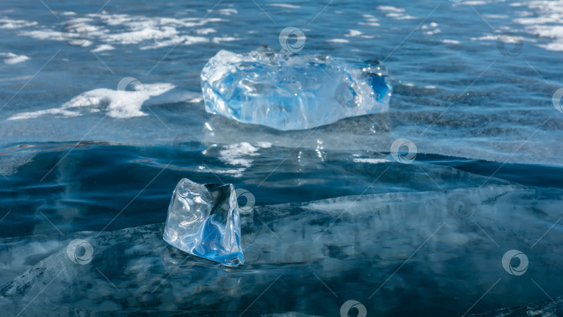 Скачать Блестящие осколки льда лежат на гладкой голубой поверхности замерзшего озера. фотосток Ozero