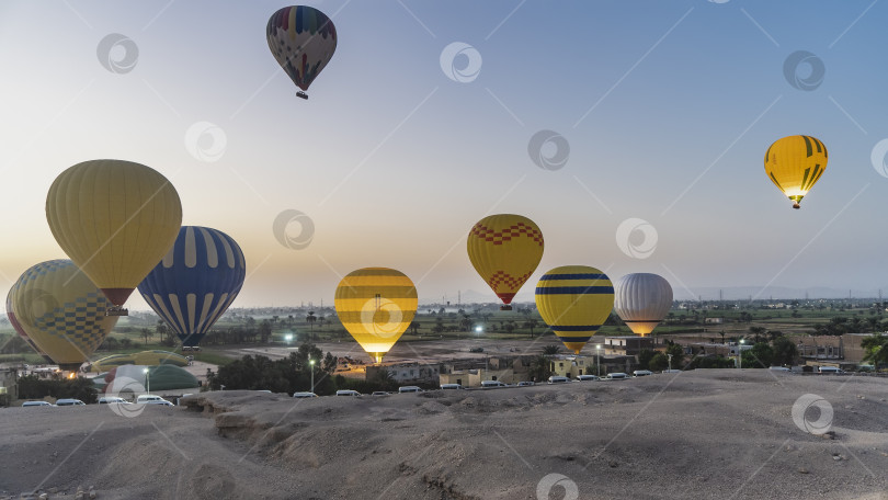 Скачать Яркие воздушные шары поднимаются в рассветное небо над пустыней в Луксоре. фотосток Ozero