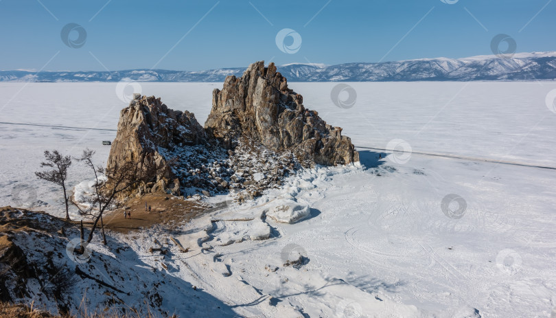 Скачать Живописная двуглавая скала, лишенная растительности, возвышается над замерзшим озером. фотосток Ozero