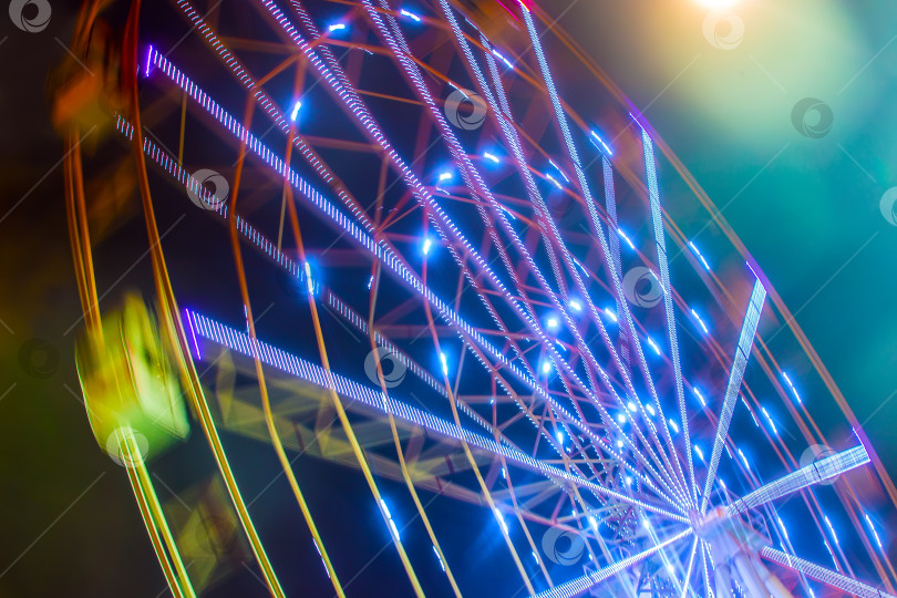 Скачать Карнавальный аттракцион, демонстрирующий вращающееся колесо обозрения в действии фотосток Ozero