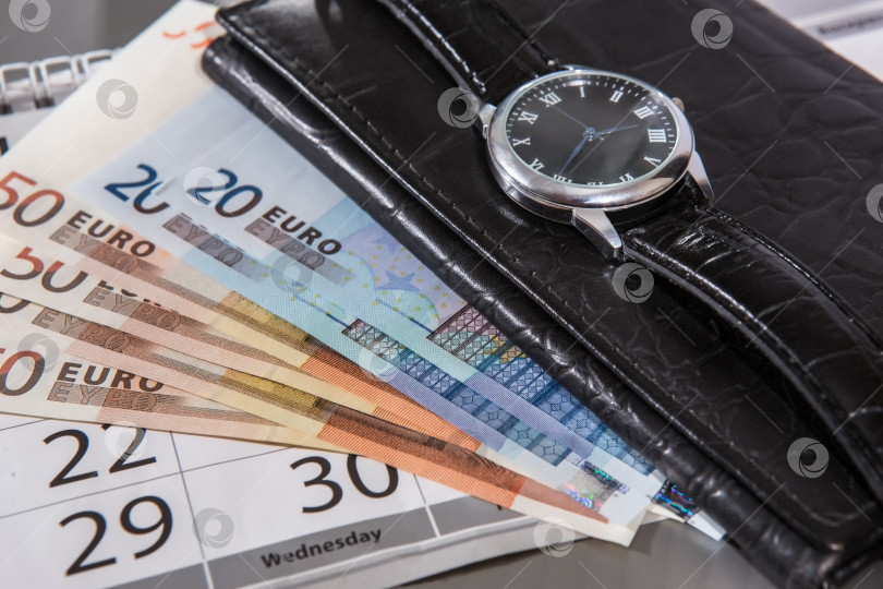 Скачать Иностранные банкноты, бумажник и наручные часы на столе. фотосток Ozero