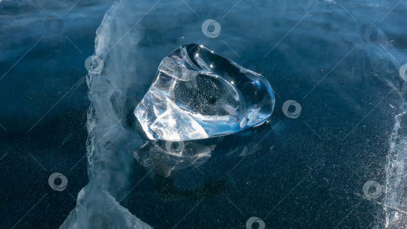 Скачать Блестящий прозрачный осколок льда на голубом замерзшем озере. фотосток Ozero