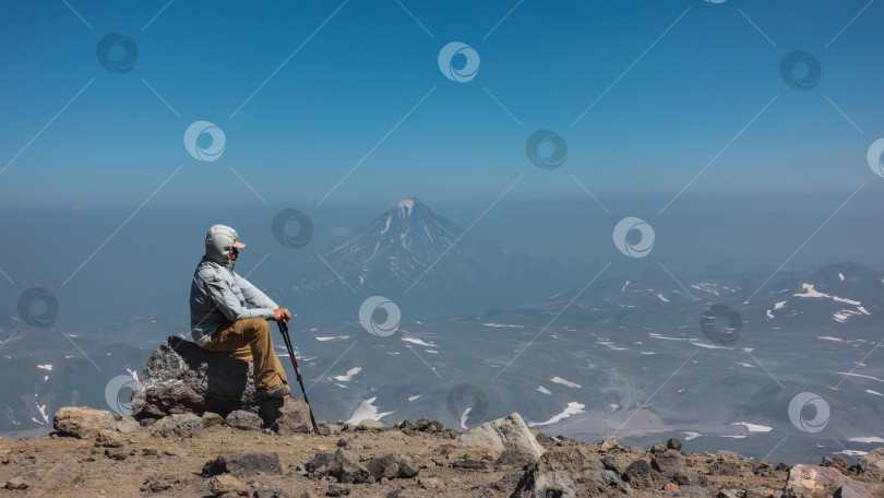 Скачать Мужчина в ветровке сидит на валуне на вершине горы фотосток Ozero