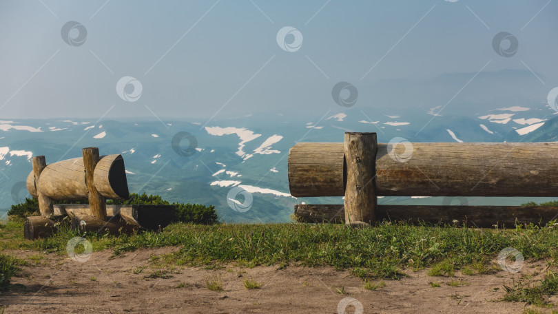 Скачать На склоне холма стоят две скамейки, сделанные из некрашеных бревен. фотосток Ozero